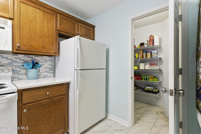 kitchen featuring backsplash, light countertops, brown cabinetry, marble finish floor, and white appliances