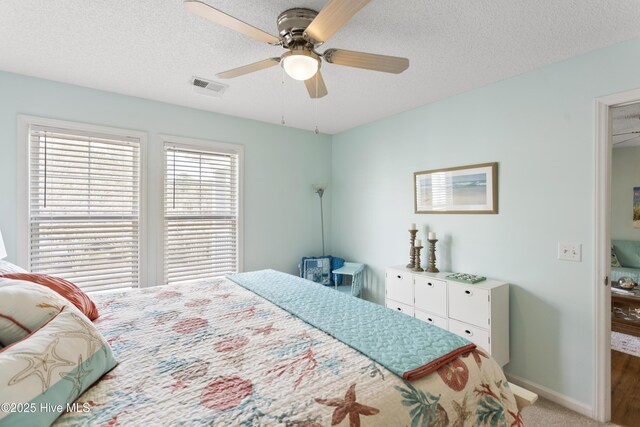 carpeted bedroom with visible vents, ceiling fan, a textured ceiling, and baseboards