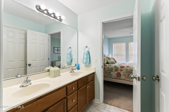 full bath featuring a sink, a textured ceiling, double vanity, and ensuite bathroom