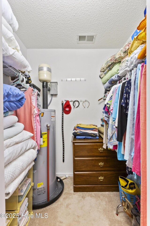 spacious closet featuring water heater, visible vents, and carpet