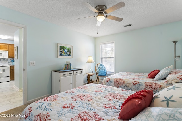 bedroom with baseboards, a ceiling fan, visible vents, and a textured ceiling