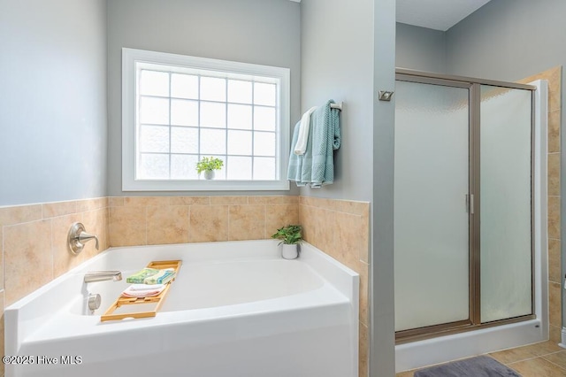 bathroom with plenty of natural light, a bath, and a stall shower
