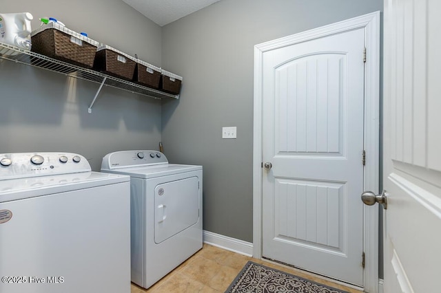 clothes washing area featuring laundry area, baseboards, and washing machine and clothes dryer