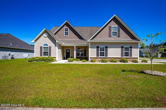 craftsman house featuring central AC unit, a front lawn, covered porch, and stone siding