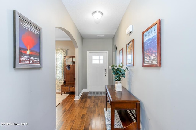 entryway with visible vents, arched walkways, baseboards, and hardwood / wood-style flooring