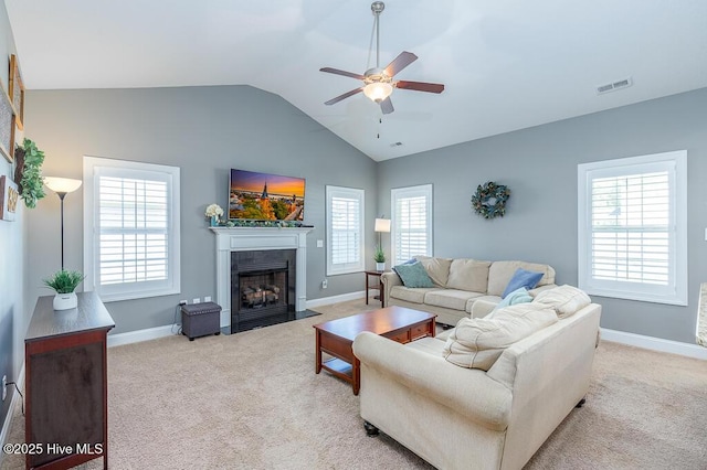 living room with carpet flooring, ceiling fan, a fireplace with flush hearth, a healthy amount of sunlight, and lofted ceiling