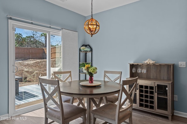 dining space featuring baseboards, a chandelier, and wood finished floors