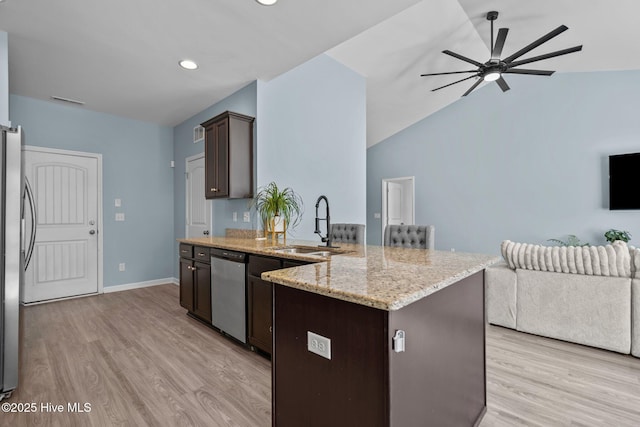 kitchen with light wood-style flooring, stainless steel appliances, a sink, open floor plan, and dark brown cabinets