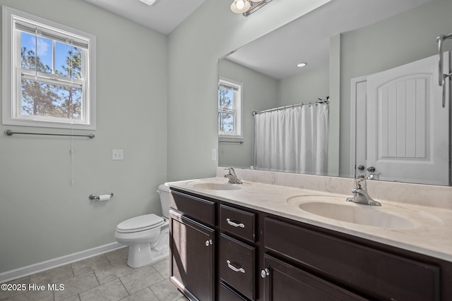 full bath featuring double vanity, tile patterned flooring, a sink, and toilet