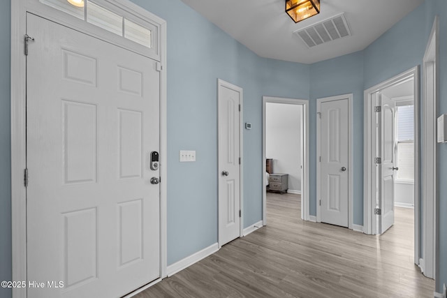 entryway with baseboards, visible vents, and wood finished floors