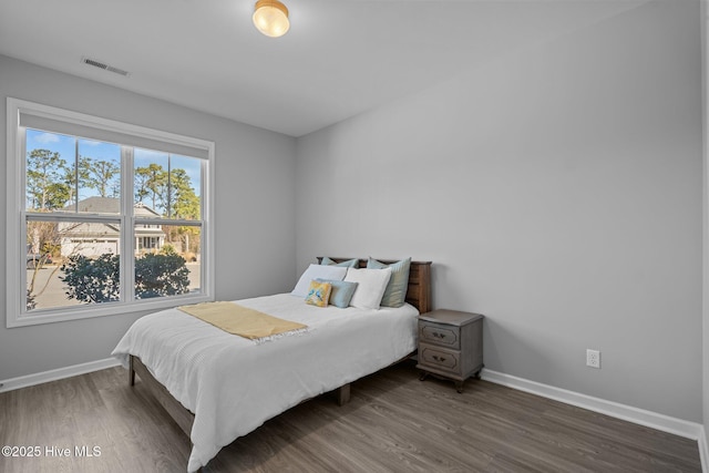 bedroom featuring wood finished floors, visible vents, and baseboards