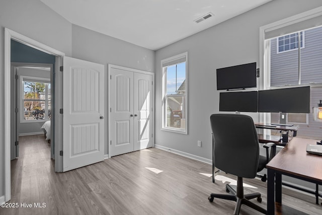 office space with baseboards, a wealth of natural light, and wood finished floors