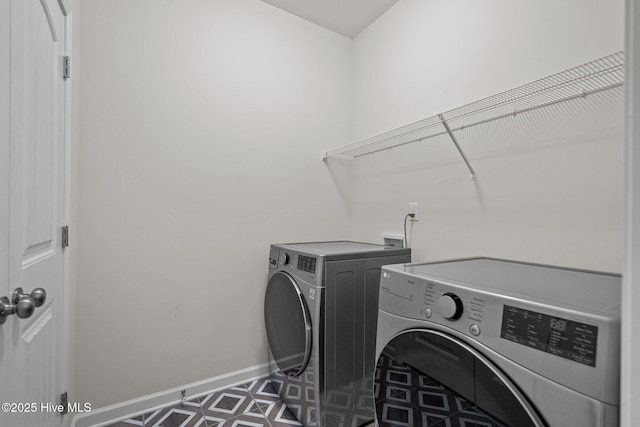 washroom with laundry area, washing machine and dryer, and baseboards