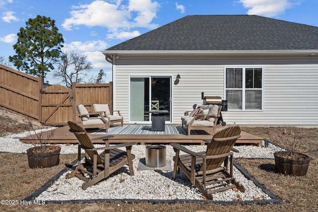 back of house with roof with shingles, fence, and a deck