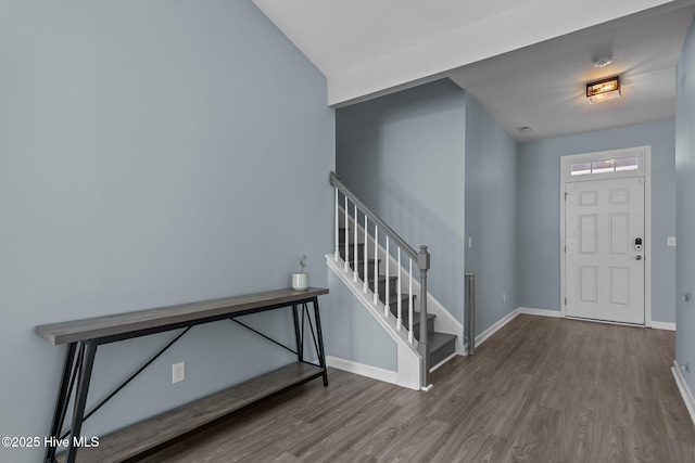 foyer featuring wood finished floors, vaulted ceiling, baseboards, and stairs