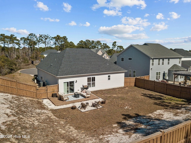 rear view of house featuring a shingled roof and a fenced backyard