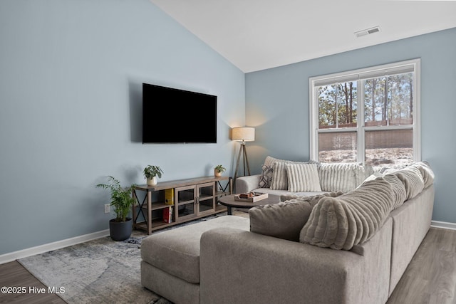 living area with lofted ceiling, visible vents, baseboards, and wood finished floors