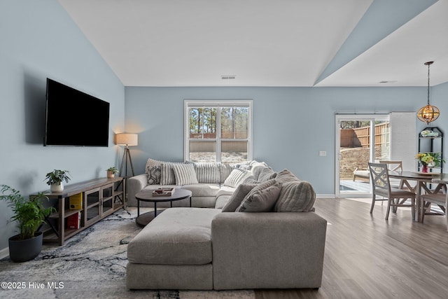 living area featuring a healthy amount of sunlight, visible vents, and vaulted ceiling