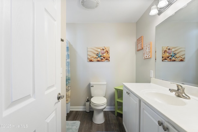 bathroom with wood finished floors, vanity, toilet, and baseboards