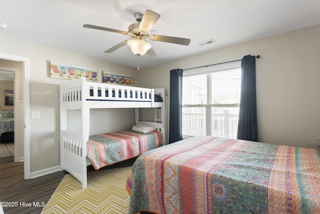 bedroom featuring a ceiling fan, visible vents, baseboards, and wood finished floors