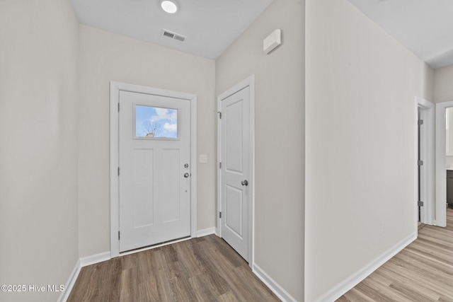 foyer with baseboards, visible vents, and wood finished floors