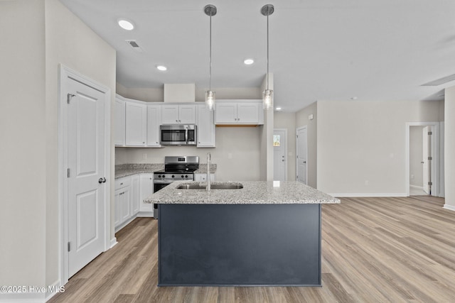 kitchen with light stone counters, visible vents, appliances with stainless steel finishes, white cabinets, and a sink