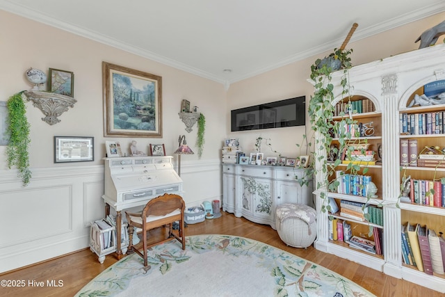 sitting room featuring wainscoting, wood finished floors, and crown molding