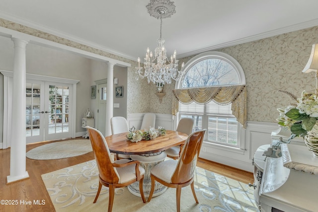 dining space featuring a wainscoted wall, crown molding, wood finished floors, and wallpapered walls