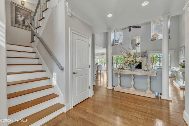 stairway with ceiling fan, recessed lighting, a high ceiling, wood finished floors, and decorative columns