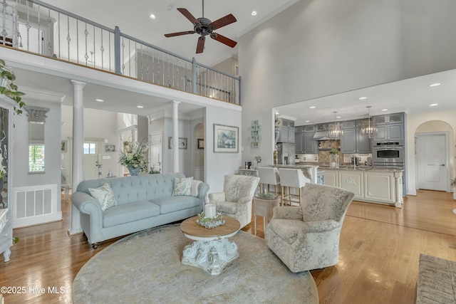 living room with arched walkways, light wood-style flooring, recessed lighting, visible vents, and a ceiling fan