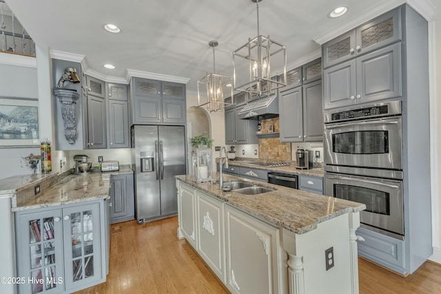 kitchen with gray cabinetry, appliances with stainless steel finishes, ornamental molding, a sink, and under cabinet range hood