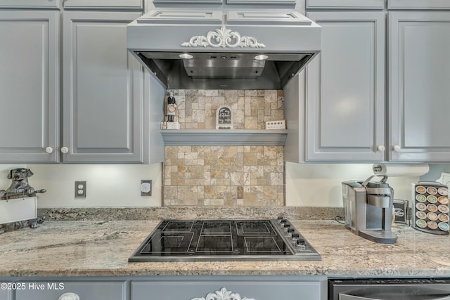 kitchen featuring tasteful backsplash, premium range hood, light stone counters, and black electric stovetop