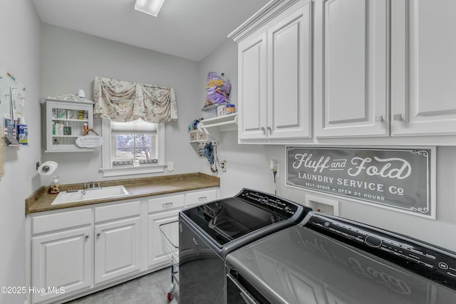 washroom featuring cabinet space, washing machine and dryer, and a sink