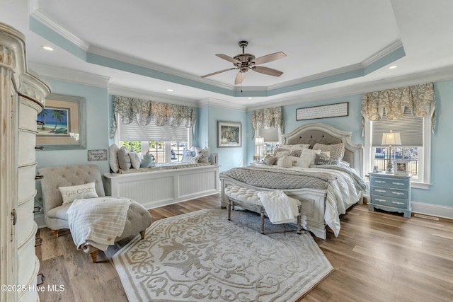 bedroom with ornamental molding, a tray ceiling, and wood finished floors