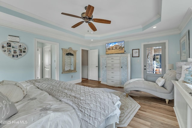 bedroom featuring a ceiling fan, a tray ceiling, wood finished floors, and ornamental molding