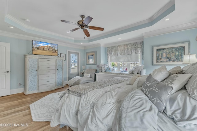 bedroom with ornamental molding, a raised ceiling, and light wood-style flooring