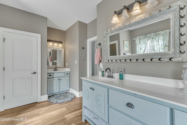 bathroom with two vanities, a sink, baseboards, and wood finished floors