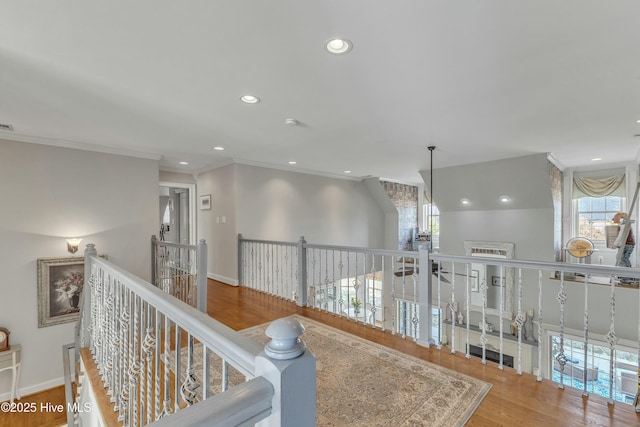 hall with recessed lighting, wood finished floors, an upstairs landing, and crown molding