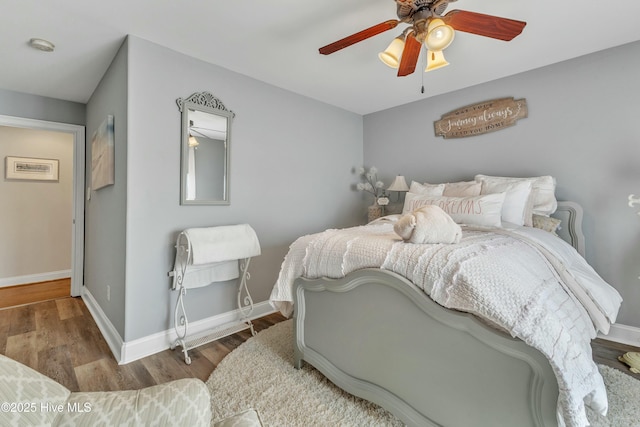 bedroom featuring wood finished floors, a ceiling fan, and baseboards