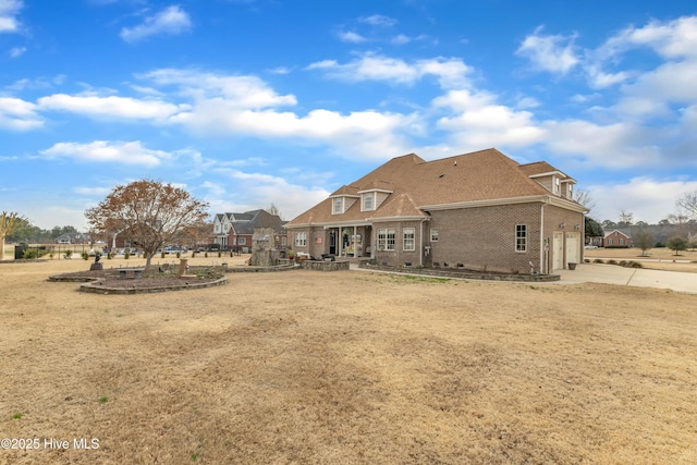 rear view of house featuring concrete driveway and brick siding