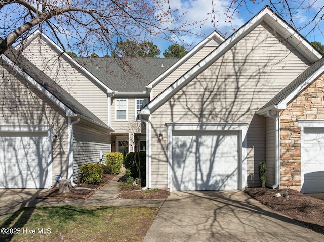 traditional-style house with an attached garage, stone siding, and concrete driveway