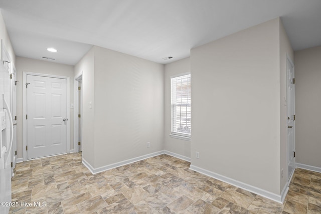 spare room with stone finish floor, visible vents, baseboards, and recessed lighting