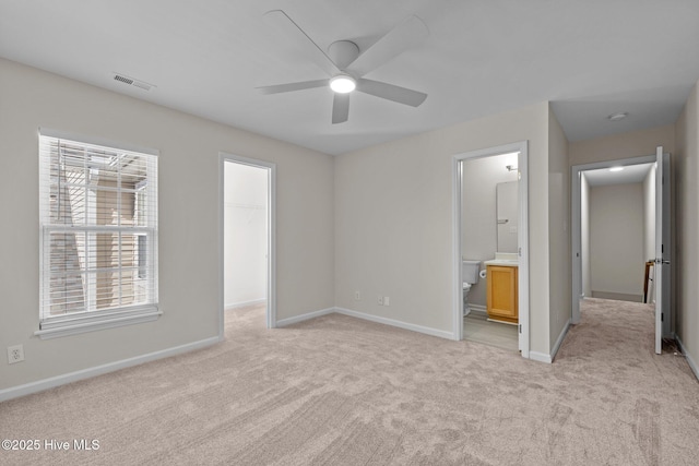 unfurnished bedroom with a spacious closet, light colored carpet, visible vents, and baseboards