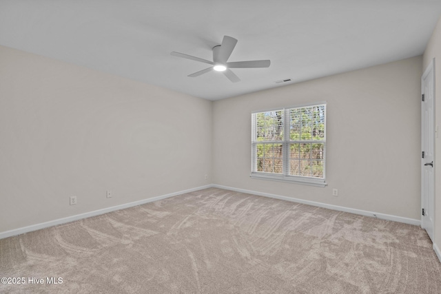 carpeted spare room featuring baseboards, visible vents, and a ceiling fan