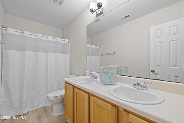 bathroom featuring toilet, a sink, and visible vents