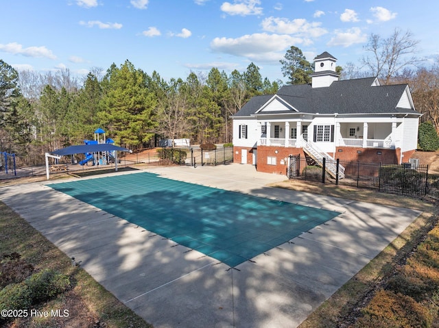 view of swimming pool with stairs, a playground, fence, and a patio