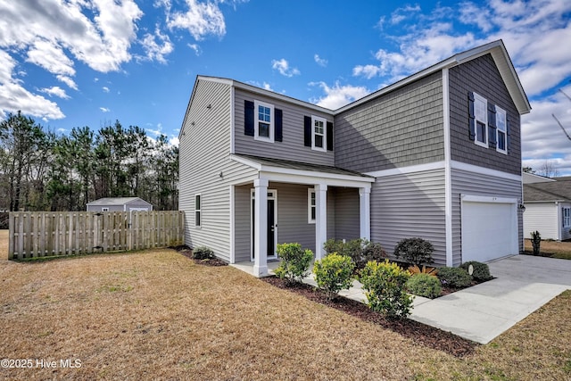 traditional-style house featuring an attached garage, fence, a front lawn, and concrete driveway