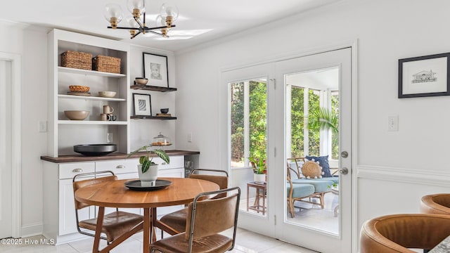 dining area featuring light tile patterned floors, ornamental molding, and a notable chandelier