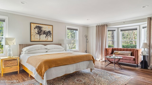 bedroom featuring ornamental molding, multiple windows, and wood finished floors