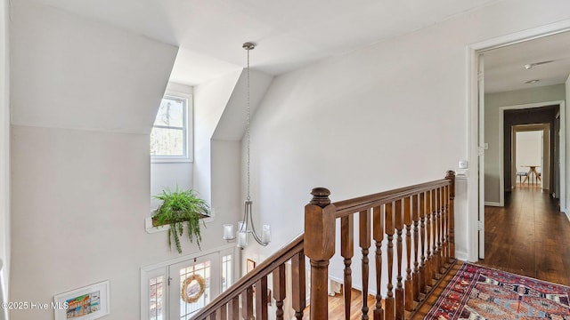 hall with lofted ceiling, wood finished floors, and an upstairs landing